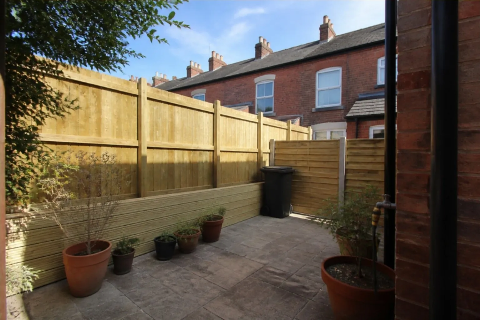 Back yard of a red-brick terraced house with a new timber fence along one side